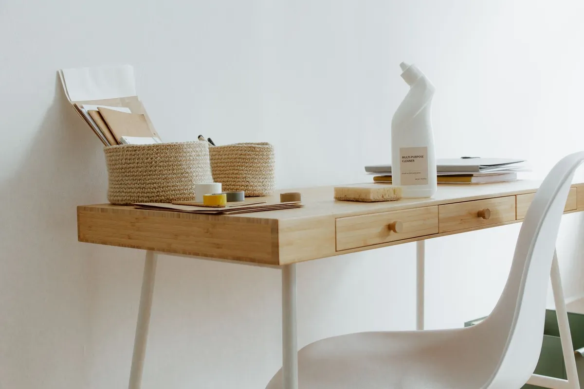 A tidy home office desk with cleaning products and organized papers, highlighting the value of professional cleaning.